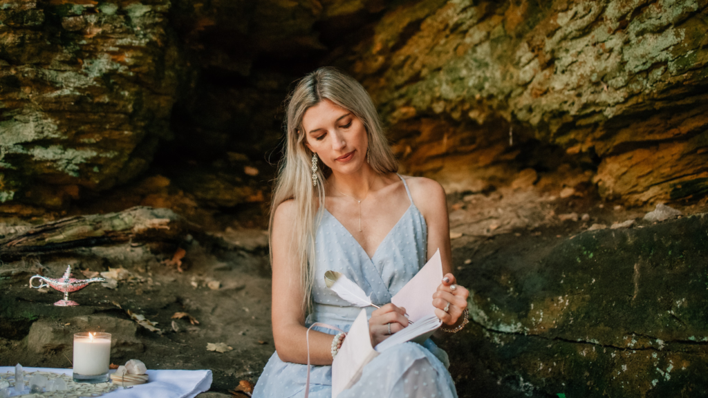 A healer sitting on a rock with a journal and a feather pen,  setting intentions after learning how to set intentions that actually manifest