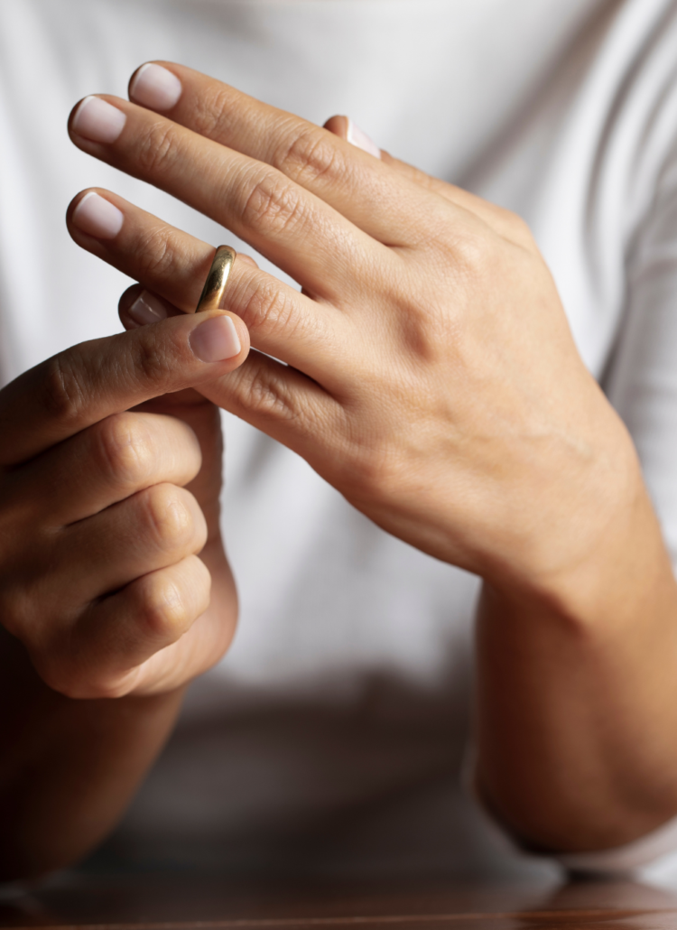 Hands of female who is about to take off her wedding ring representing 3 steps to overcome divorce